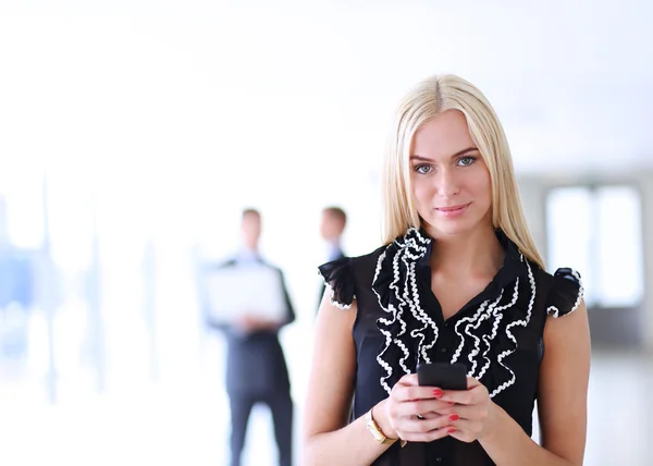 Красивая деловая женщина с мобильным телефоном, стоящая в офисе Стоковая Картинка