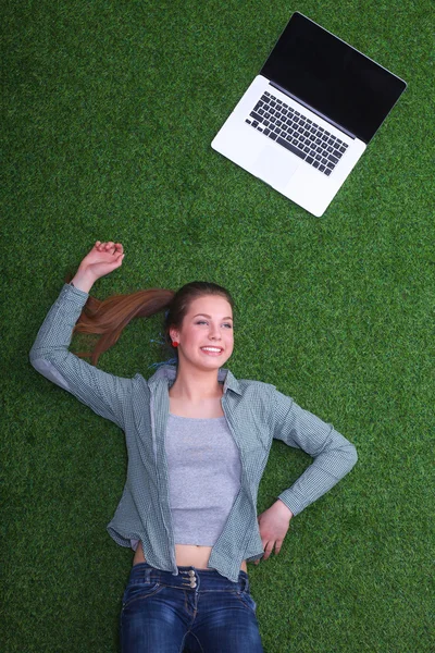 年轻女子躺在草地上，一台笔记本电脑 — 图库照片