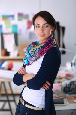 Güzel moda tasarımcısı stüdyoda duruyor.