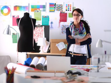 Güzel moda tasarımcısı stüdyoda duruyor.