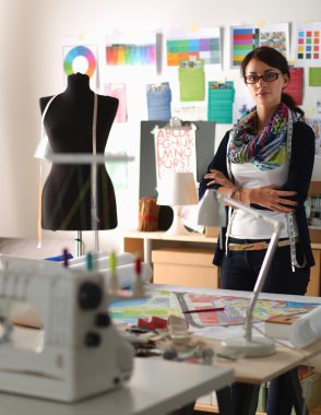 Güzel moda tasarımcısı stüdyoda duruyor.