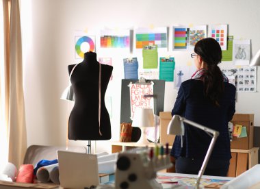 Güzel moda tasarımcısı stüdyoda duruyor.