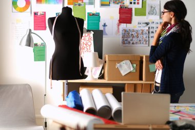 Güzel moda tasarımcısı stüdyoda duruyor.