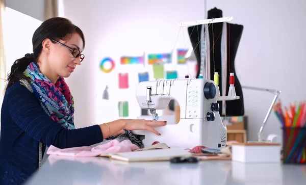 Mujer joven cosiendo sentado en su lugar de trabajo — Foto de Stock