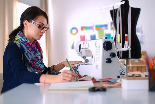 Mujer joven cosiendo sentado en su lugar de trabajo — Foto de Stock