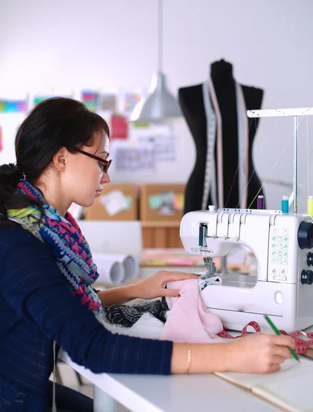 Mujer joven cosiendo sentado en su lugar de trabajo — Foto de Stock