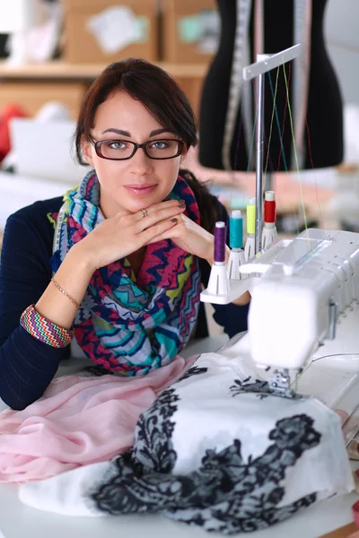 Schöne Modedesignerin sitzt am Schreibtisch im Atelier — Stockfoto