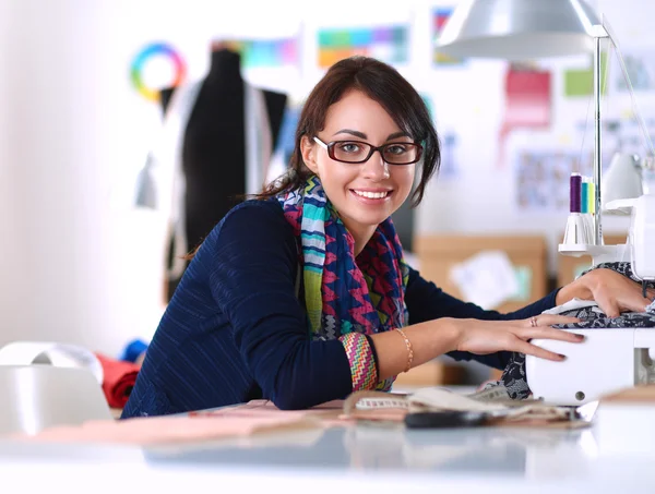 Young woman sewing while sitting at her working place — Stock Photo, Image