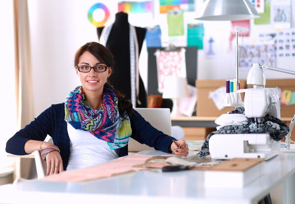 Beautiful fashion designer sitting at the desk in studio