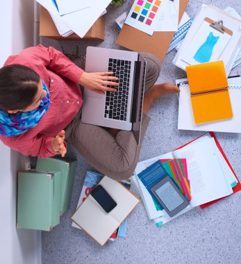 Öğrenci kitap ile bir dizüstü bilgisayarda çalışma etrafında yaymak