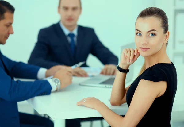 Porträtt av en vacker affärskvinna som sitter på ett kontor med kollegor i bakgrunden — Stockfoto