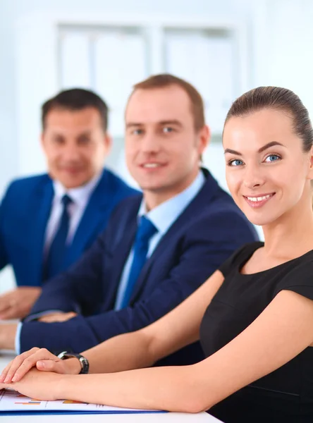 Porträt einer schönen Geschäftsfrau, die in einem Büro sitzt, mit Kollegen im Hintergrund — Stockfoto