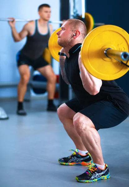 Pazı gerçekleştirme genç bir adam çekim bir spor salonunda bukleler — Stok fotoğraf