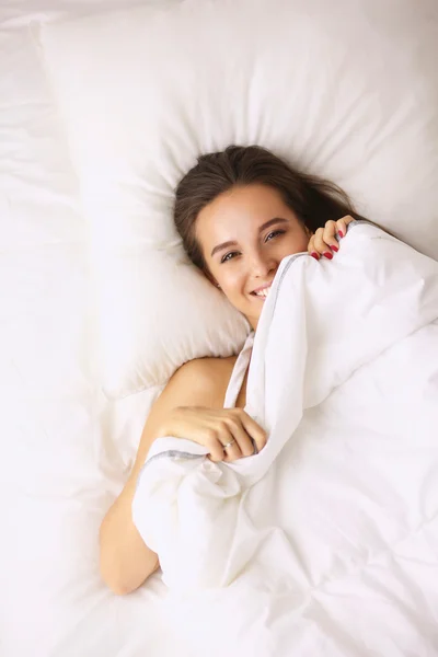 En ganska ung kvinna Tjuvkika från under täcket i hennes sovrum happilly — Stockfoto