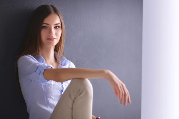 Mujer joven sentada en el suelo cerca de la pared oscura — Foto de Stock