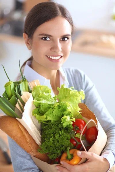 一个拿着蔬菜购物袋站在厨房里的年轻女人 — 图库照片
