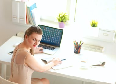 Masasında ve bilgisayarında evrakları olan bir kadın.