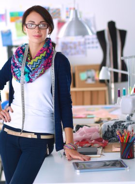 Güzel moda tasarımcısı stüdyoda duruyor.