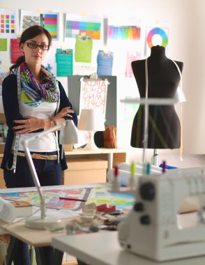 Güzel moda tasarımcısı stüdyoda duruyor.