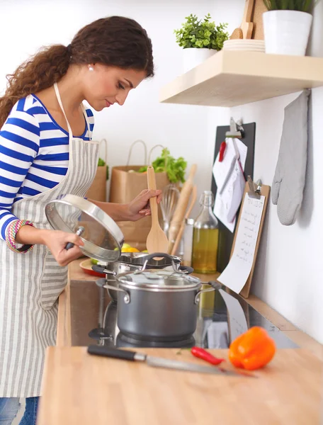 Smiling young woman in the kitchen, isolated on background — Stock Photo, Image