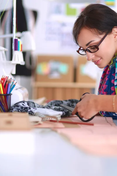 Mode-ontwerper snijden textiel naast een naaimachine — Stockfoto