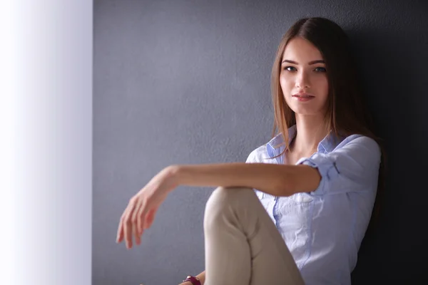 Mujer joven sentada en el suelo cerca de la pared oscura —  Fotos de Stock