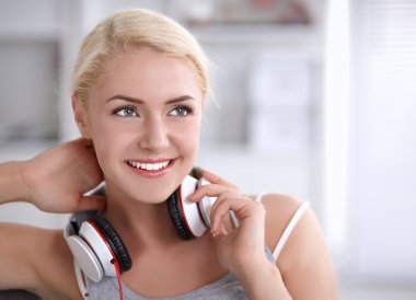 Evdeki genç ve güzel kadın kanepede oturup müzik dinliyor.