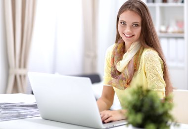 Elinde evrakları olan kadın masanın üstünde oturuyor.