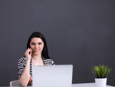 Masasında kulaklığı ve laptopuyla çalışan güzel bir iş kadını.