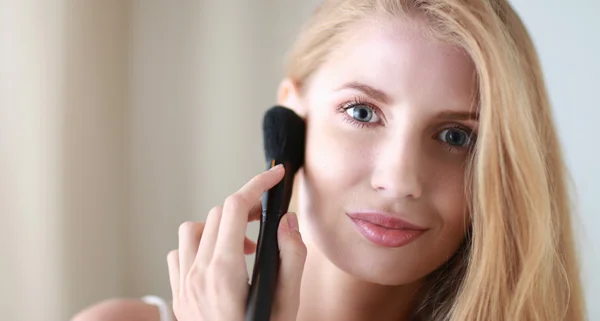 Bonita mujer aplicando maquillaje con cepillo — Foto de Stock