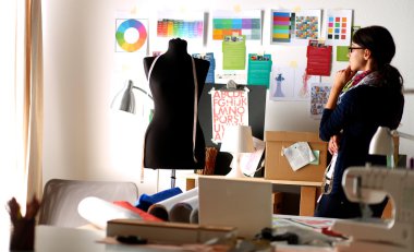 Güzel moda tasarımcısı stüdyoda duruyor.