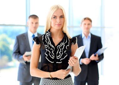 İçinde belgili tanımlık geçmiş meslektaşları ile bir ofiste duran bir güzel ofis çalışanı portresi