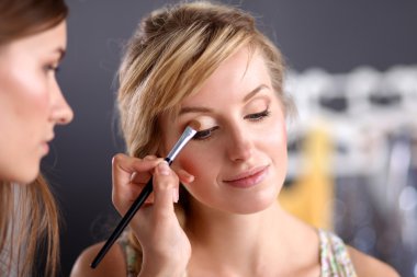 Kadından profesyonel makyaj yapan sanatçı.