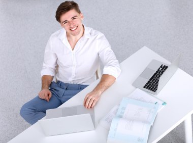 Genç işadamı ofiste çalışıyor, masada oturuyor.