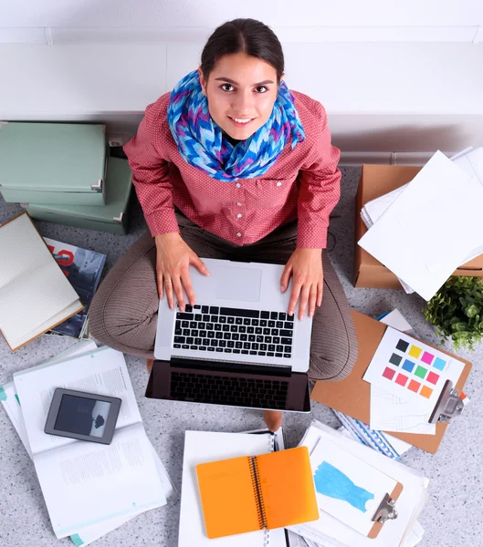 Student with books spread around working on a laptop — Stock Photo, Image