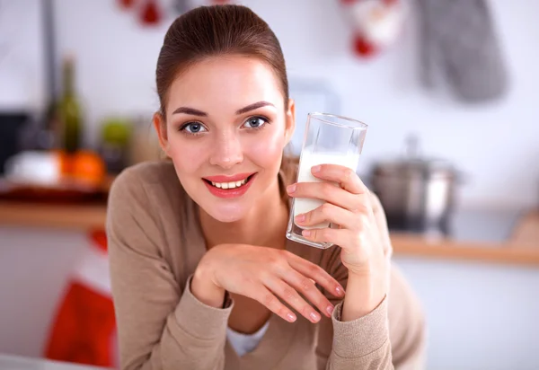 Una joven con un vaso de leche en su cocina —  Fotos de Stock