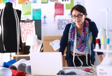 Güzel moda tasarımcısı stüdyoda duruyor.