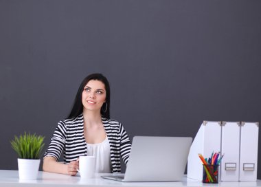 Gri arka planda dizüstü bilgisayarı olan genç bir kadın.