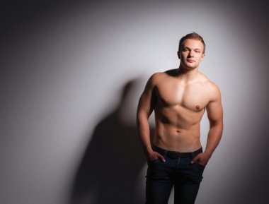 Karanlık bir arka plan üzerinde ayakta sağlıklı kas genç adam