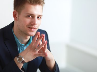 Genç işadamı ofiste çalışıyor, masada oturuyor.