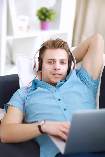Man listening music in headphone on the sofa at home — Stock Photo, Image