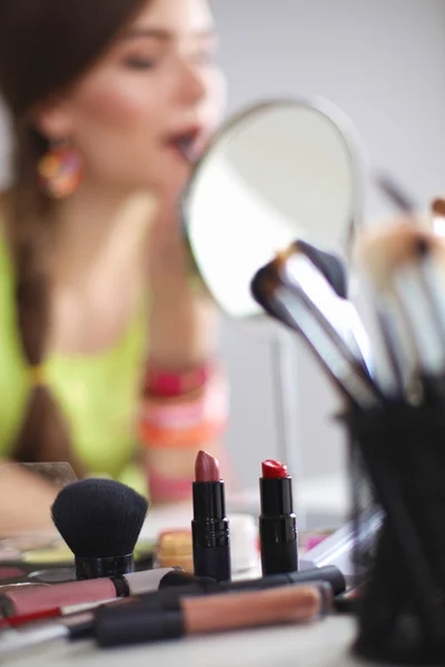 年轻漂亮的女人，使附近镜子，坐在办公桌前的化妆 — 图库照片