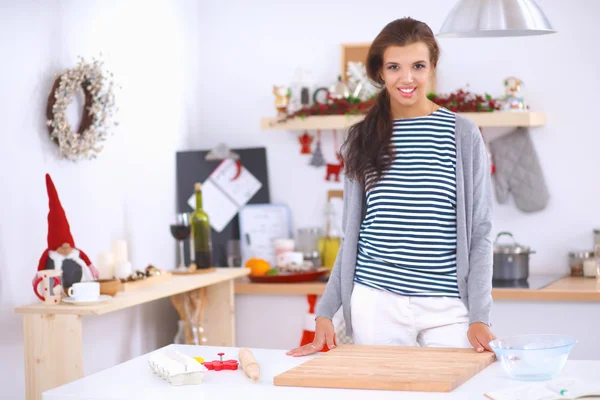 Mujer joven sonriente en la cocina, aislada en el fondo de Navidad — Foto de Stock