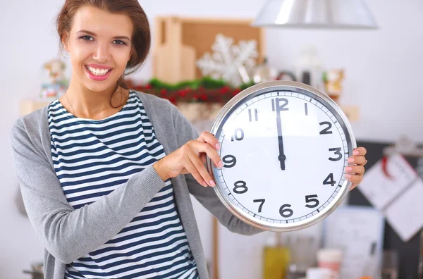 Gelukkig jong vrouw tonen klok in kerst versierd keuken — Stockfoto