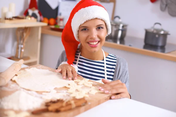 Χαρούμενη νεαρή γυναίκα χαμογελώντας χαρούμενη διασκεδάζοντας με τις Χριστουγεννιάτικες προετοιμασίες φορώντας το καπέλο του Άη Βασίλη — Φωτογραφία Αρχείου