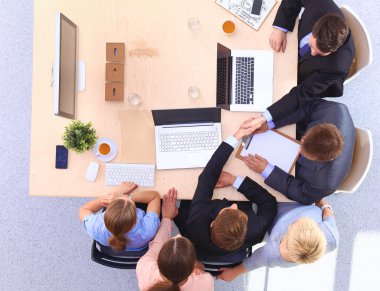 İş adamları el sıkışır, masada otururlar.