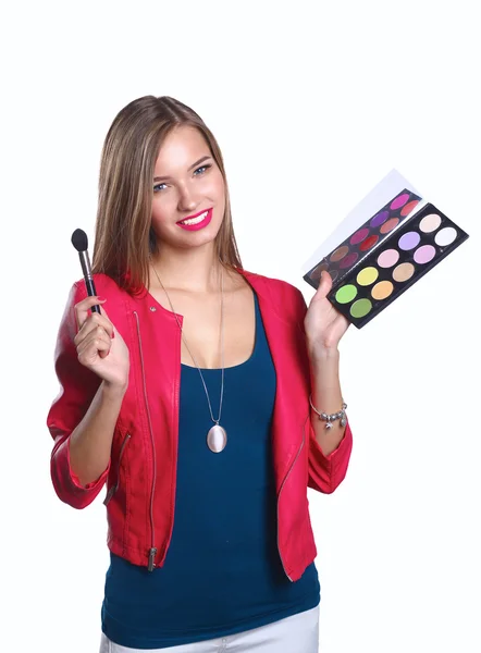 Jeune belle femme tient dans une main et une palette avec de la peinture et des ombres pour le maquillage, brosse d'occasion pour le maquillage — Photo