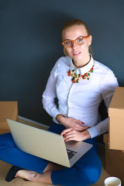 Frau sitzt auf dem Boden neben einer Schachtel mit Laptop — Stockfoto