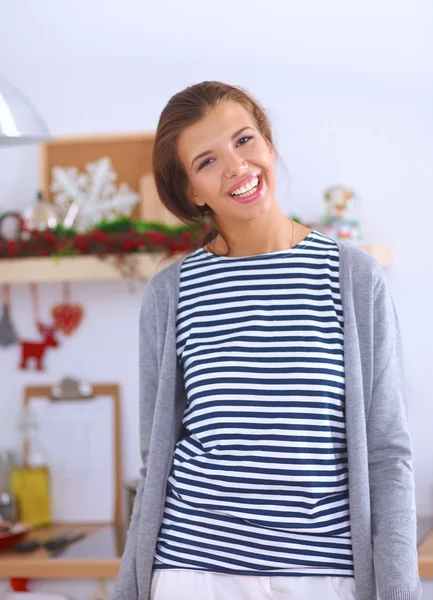 Mujer joven sonriente en la cocina, aislada en el fondo de Navidad — Foto de Stock