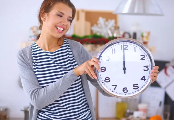 Gelukkig jong vrouw tonen klok in kerst versierd keuken — Stockfoto